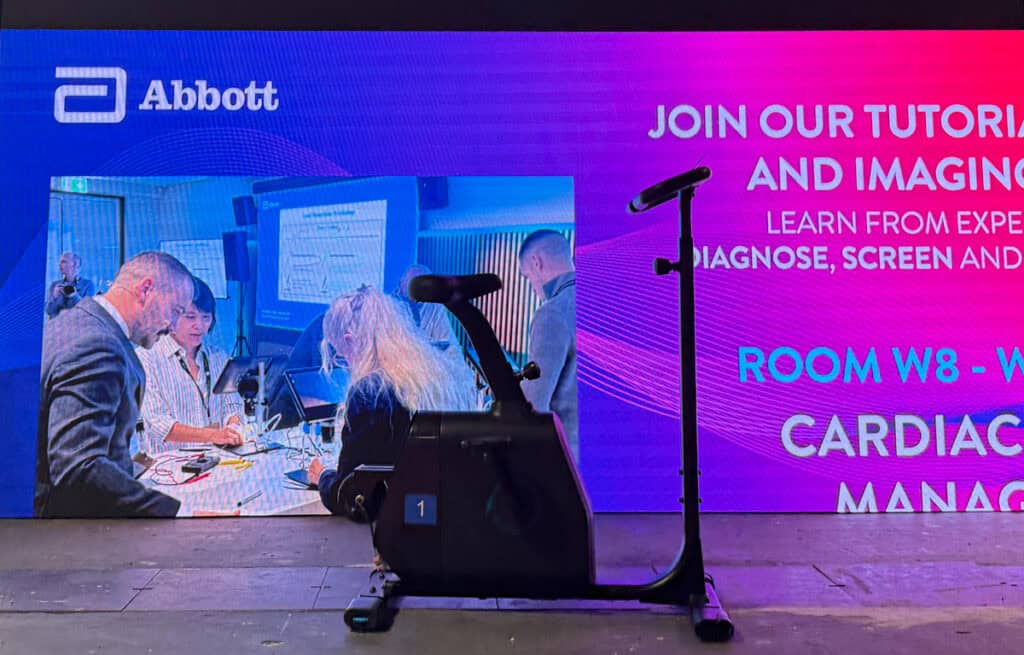 Bicicleta generadora frente a pantalla LED interactiva en evento Abbott